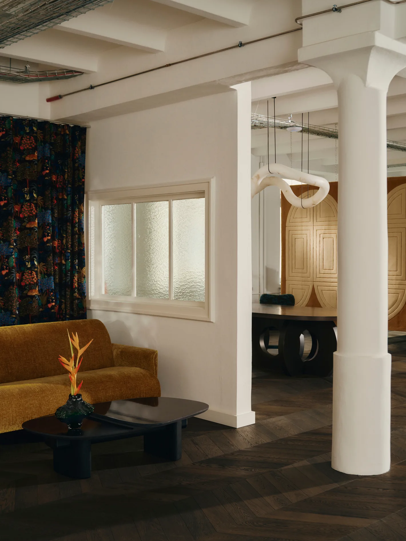 Lounge at Le Comptoir with white columns, a mustard sofa and a patterned curtain. Photo: Conny Mirbach