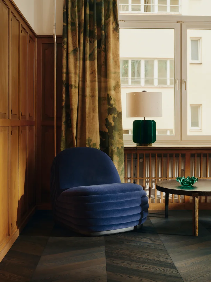 Blue velvet lounge chair in front of a tapestry curtain. Photo: Conny Mirbach