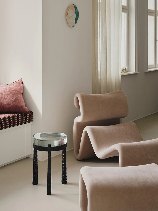 Sculptural pink lounge chairs and a glass side table by the window.