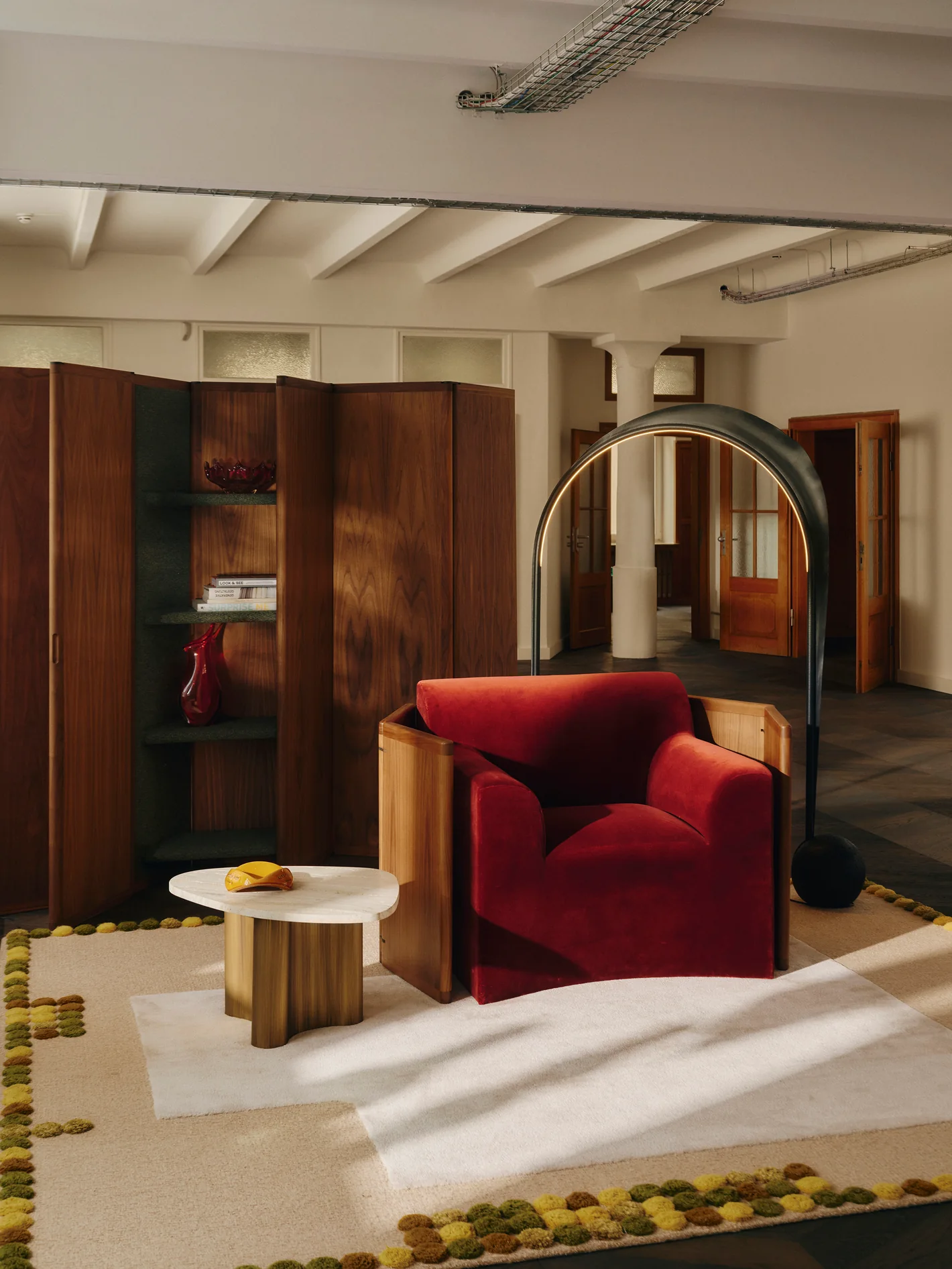 Red armchair, a round side table and a wooden cabinet on a hand-tufted rug at Le Comptoir. Photo: Conny Mirbach